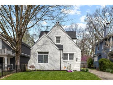 Charming white brick home with well-manicured lawn and fresh spring flowers at 402 E 46Th St, Indianapolis, IN 46205