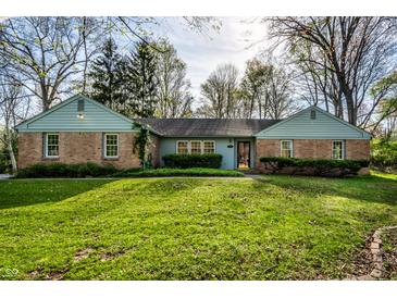 Charming brick home with a well-manicured lawn and beautiful landscaping at 6911 N Tuxedo St, Indianapolis, IN 46220