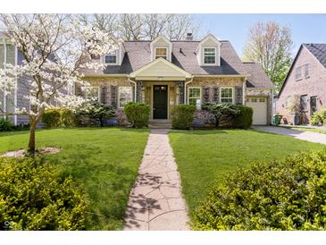 Charming brick home with beautiful front lawn, landscaping, and welcoming stone walkway at 908 N Bolton Ave, Indianapolis, IN 46219