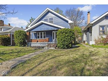 Charming blue two-story home with a cozy front porch, landscaped yard and brick accents, located in a neighborhood setting at 914 N Bancroft St, Indianapolis, IN 46201