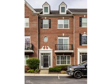 Charming brick townhouse featuring black shutters, dormer windows, and a well-maintained front garden at 1057 3Rd Nw Ave, Carmel, IN 46032
