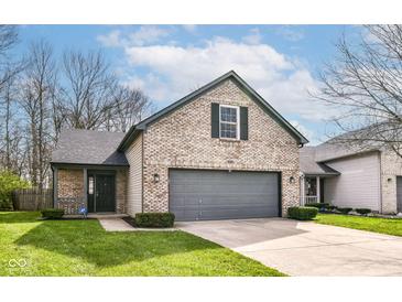 Charming brick home featuring an attached gray two-car garage and well manicured lawn at 10839 Cedar Pine Dr, Indianapolis, IN 46235