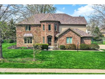 Charming two-story brick home with a well-manicured lawn and a beautiful, mature tree in the front yard at 1444 Trail Creek Ct, Carmel, IN 46032