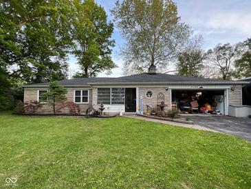 Charming ranch-style home featuring a well-manicured lawn and an attached garage overflowing with possessions at 3155 W 57Th St, Indianapolis, IN 46228