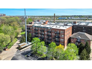 Brick exterior of the H. Lauter Lofts, featuring private balconies and a visible parking lot at 55 S Harding St # 301, Indianapolis, IN 46222