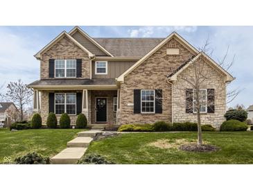 Inviting two-story brick home with a well-manicured lawn and charming front porch at 5869 Belchamp Dr, Noblesville, IN 46062