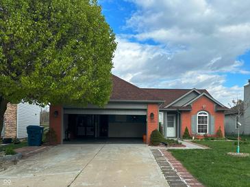 Charming brick home with an attached garage, well-manicured lawn, and beautiful landscaping at 7201 Barnwell Pl, Indianapolis, IN 46217
