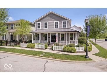 Charming two-story home boasts a welcoming front porch and a well-manicured lawn with a classic white picket fence at 7638 Beekman Ter, Zionsville, IN 46077