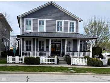 Charming two-story home featuring a welcoming front porch with a white picket fence and attractive landscaping at 7638 Beekman Ter, Zionsville, IN 46077
