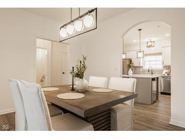 Bright dining room boasts modern chandelier and flows into kitchen, creating inviting and open space at 861 S Park Trail Dr, Carmel, IN 46032