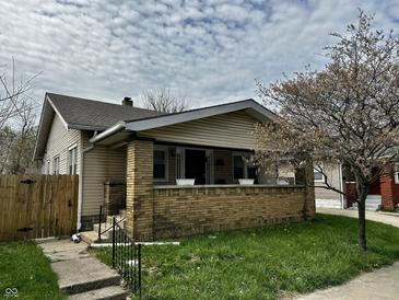Charming single-story home with a brick porch and a well-maintained front yard, complemented by a mature tree at 1020 N Colorado Ave, Indianapolis, IN 46201