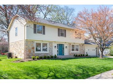 Charming two-story home featuring stone accents, a well-manicured lawn, and a bright blue front door at 3738 Barrington Dr, Carmel, IN 46033