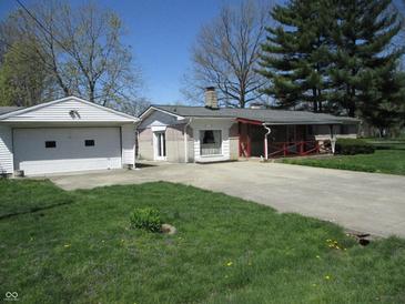 Quaint home featuring a front porch, chimney, detached garage, and well-maintained lawn at 7402 Alice Ave, Indianapolis, IN 46219