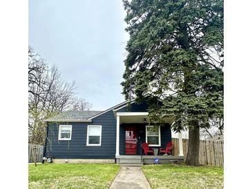 Charming home featuring a covered porch with red chairs and a well-maintained lawn at 1624 N Whittier Pl, Indianapolis, IN 46218