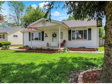 Inviting single-story home with a welcoming front porch and lush green lawn at 1629 N K St, Elwood, IN 46036