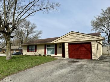 Ranch-style home featuring a red garage door, lush green lawn, and a paved driveway at 3841 Monica Ct, Indianapolis, IN 46226