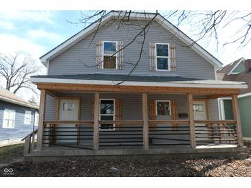 Two-story gray home with a covered front porch with decorative wood detailing and two front doors at 425 N Grant Ave, Indianapolis, IN 46201