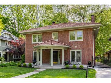 Beautiful two-story brick home featuring a unique red tile roof, inviting front porch, and lovely yard at 4343 N Pennsylvania St, Indianapolis, IN 46205