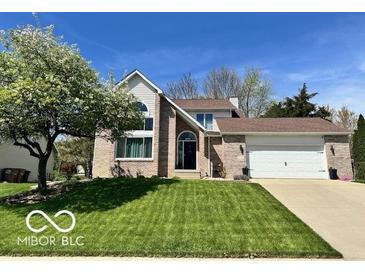 Charming two-story brick home featuring a well-manicured lawn and attached two car garage at 6036 Chinkapin Dr, Columbus, IN 47201