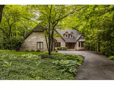 Charming brick home with mature trees, landscaping, and a circular driveway at 7249 Tuliptree Trl, Indianapolis, IN 46256