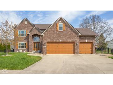 Lovely brick home featuring a three-car garage, manicured lawn, and stylish wooden window shutters at 1121 Retford Ct, Greenwood, IN 46143