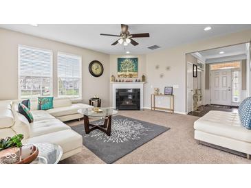 Bright living room featuring a fireplace, a ceiling fan, and ample natural light at 1334 Winfield Way, Greenwood, IN 46143