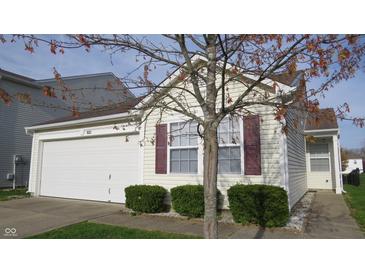 Charming home featuring an attached garage, neat shrubbery, and classic neutral siding at 1833 Southernwood Ln, Indianapolis, IN 46231
