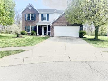 Charming two-story brick home with a two-car garage and well-manicured lawn on a sunny day at 2303 Cole Wood Ct, Indianapolis, IN 46239