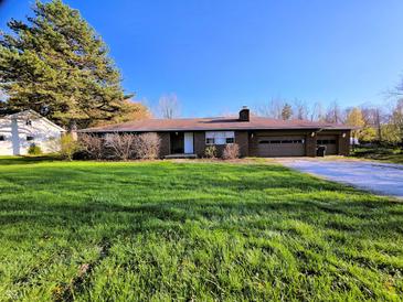 Brick ranch home with an attached two car garage and large front yard under a clear blue sky at 935 Fry Rd, Greenwood, IN 46142
