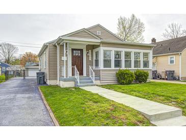 Charming bungalow with tan siding, a manicured lawn, and inviting front porch at 2009 N Bosart Ave, Indianapolis, IN 46218