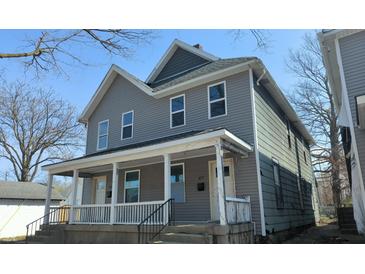 Two story home with a grey exterior and a covered front porch with white trim and railing at 437 Jefferson Ave, Indianapolis, IN 46201