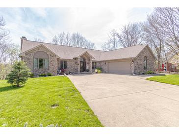 Charming brick home with well-manicured lawn, mature trees, and long driveway leading to an attached garage at 5875 Annanhill Ct, Avon, IN 46123