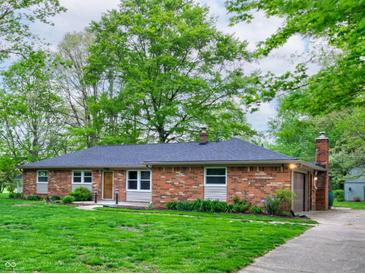 Charming brick home with an attached garage, beautiful lawn, and mature trees at 7180 W Sacramento Dr, Greenfield, IN 46140