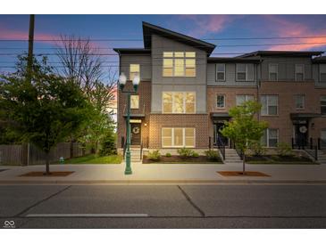Charming townhouse complex with modern design and brick accents, enhanced by decorative street lighting at dusk at 8180 E 116Th St, Fishers, IN 46038