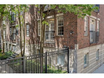 Exterior angle view of a brick apartment building with black metal balconies and a fenced yard at 226 N Cleveland St # 226C, Indianapolis, IN 46204