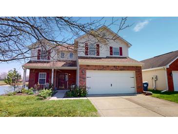 Inviting two-story home features a brick facade, red shutters, attached two car garage, and lakeside lot at 2441 Longleaf Dr, Greenwood, IN 46143