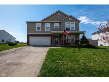Charming two-story home features a manicured lawn and a welcoming front porch with an American flag displayed at 717 Driftwood Cir, Danville, IN 46122