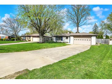 Charming single-story home features a long driveway and well-manicured lawn with mature trees and a two car garage at 731 Oak Dr, Greenwood, IN 46142