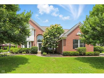 Charming two-story brick home with a manicured lawn and mature trees, creating a welcoming curb appeal at 9318 Windrift Way, Zionsville, IN 46077