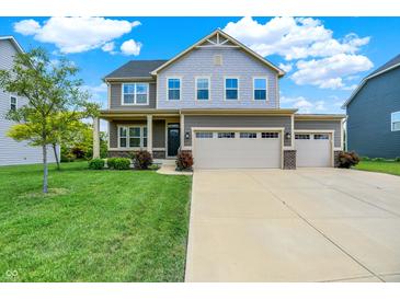Charming two-story home with a three-car garage and well-manicured lawn on a sunny day at 13567 Moorcroft Dr, Fishers, IN 46037