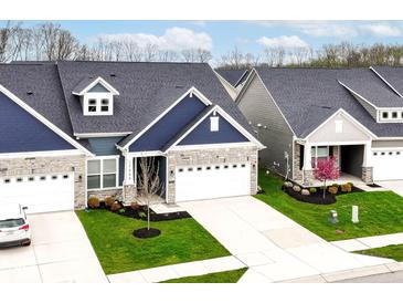 Beautiful home with stone accents, a blue exterior, attached garage, and well-maintained landscaping at 17066 Cole Evans Dr, Noblesville, IN 46060