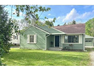 Charming one-story home with green siding, a well-manicured lawn, and beautiful landscaping at 2404 Wildwood Ave, Anderson, IN 46011