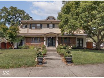 Inviting two-story home with manicured lawn and attractive landscaping, providing charming curb appeal at 3128 E Fall Creek Pkwy N Dr, Indianapolis, IN 46205