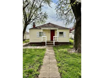 Charming home featuring a red door, white trim, walkway, and a well-maintained yard at 3136 Foltz St, Indianapolis, IN 46221