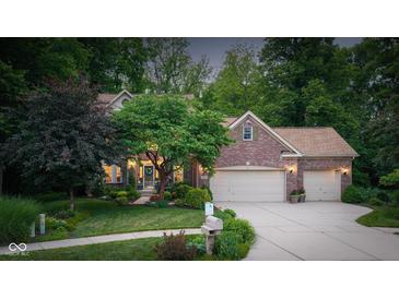 Charming brick home with a well-manicured lawn, mature trees, and a spacious driveway leading to a two-car garage at 4541 Greenthread Ct, Zionsville, IN 46077