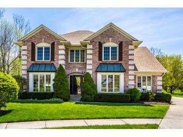 Charming two-story brick home with manicured lawn and lush greenery on a sunny day at 4731 Moss Creek Ct, Indianapolis, IN 46237