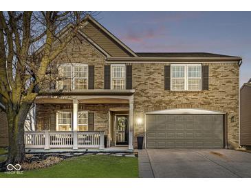 Charming two-story brick home with attached garage, covered porch, and manicured front lawn at 8327 Andrusia Ln, Indianapolis, IN 46237