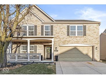 Inviting two-story brick home featuring a charming front porch and an attached two-car garage at 8327 Andrusia Ln, Indianapolis, IN 46237