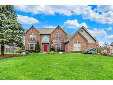 Beautiful brick two-story home with a well-manicured lawn and a bright red front door at 9319 Oak Knoll Ln, Fishers, IN 46037