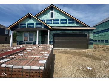 New home construction with a two-car garage, still being built with visible materials and builder wrap at 1338 Foxtail Ln, Greenwood, IN 46143
